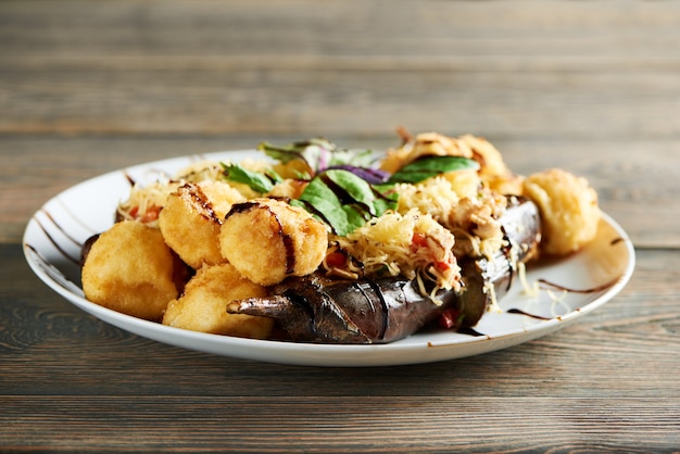 Delicioso plato caliente del restaurante, que incluye papa dorada frita con queso y jugosas verduras a la parrilla. Delicioso aperitivo decorado con hojas de menta fresca y salsa.