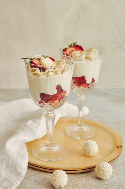 Delicioso postre de crema con trufas de coco y fresas en una tabla redonda de madera para servir