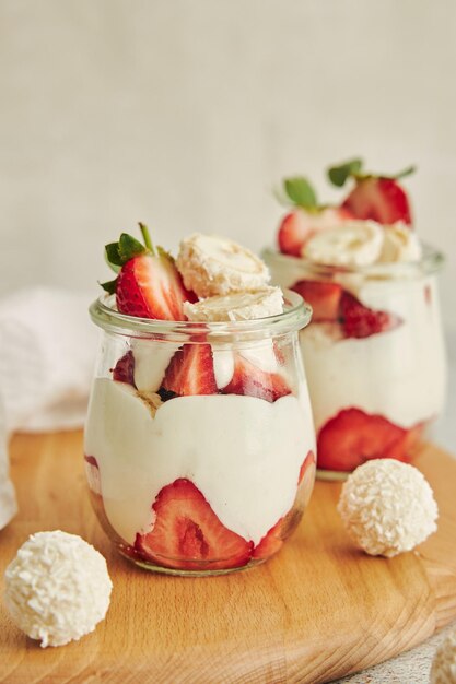 Delicioso postre de crema con trufas de coco y fresas en una tabla redonda de madera para servir