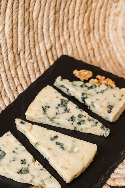 Delicioso queso azul dispuesto en fila sobre pizarra negra.