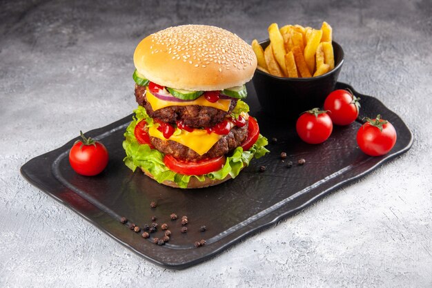 Delicioso sándwich casero y papas fritas ketchup en pizarra sobre superficie de hielo gris