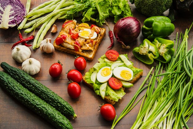 Delicioso sándwich con diferentes verduras saludables en mesa de madera