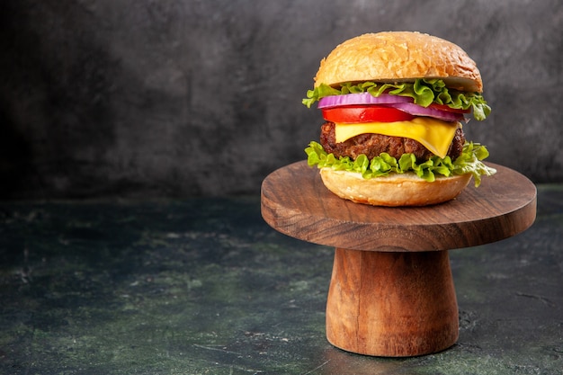 Delicioso sándwich sobre una tabla de cortar de madera en el lado izquierdo sobre una superficie de color de mezcla oscura con espacio libre