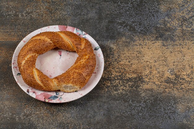 Delicioso simit con semillas de sésamo en placa colorida