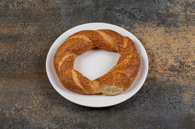 Delicioso simit con semillas de sésamo en un plato blanco.