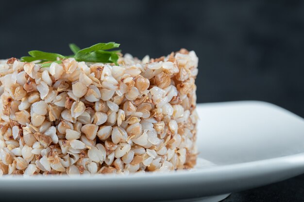 Delicioso trigo sarraceno con verduras en una placa blanca.