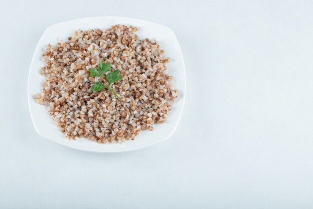 Delicioso trigo sarraceno con verduras en un plato blanco.