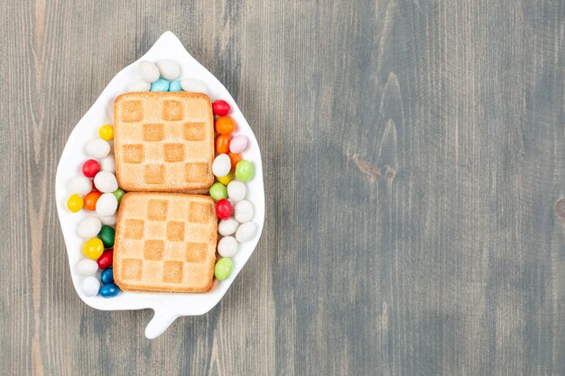 Deliciosos caramelos de colores con galletas en un plato blanco. Foto de alta calidad