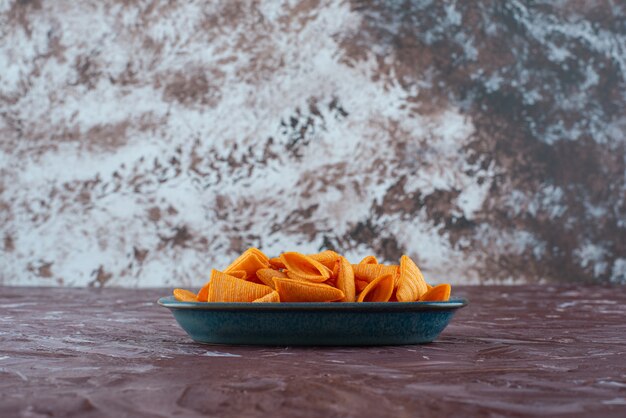 Deliciosos chips de cono en un plato sobre la superficie de mármol