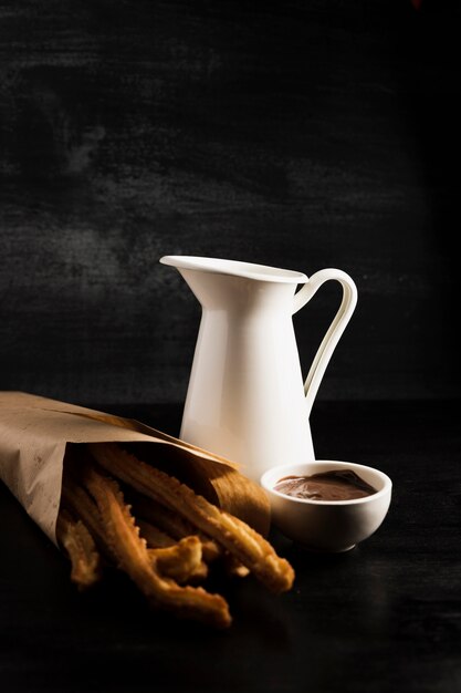 Deliciosos churros en una bolsa de papel y chocolate derretido