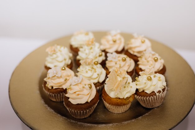 Deliciosos cupcakes con crema batida en el plato dorado