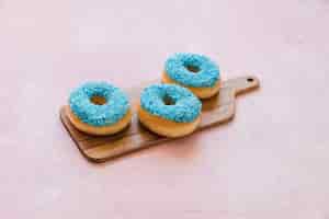 Foto gratuita deliciosos donuts azules en tabla de cortar de madera