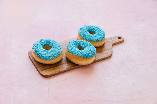 Deliciosos donuts azules en tabla de cortar de madera