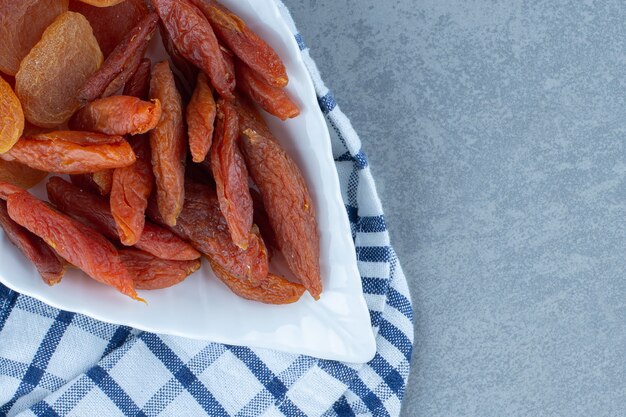 Deliciosos dos tipos de frutos secos, en un bol, sobre la toalla, sobre la mesa de mármol.