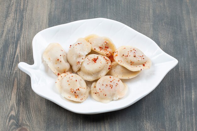 Deliciosos dumplings con pimiento rojo en una placa blanca.