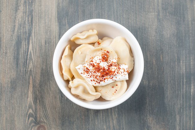 Deliciosos dumplings con pimiento rojo en un recipiente blanco