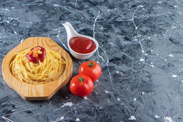 Deliciosos espaguetis en placa de madera con tomates frescos y salsa de tomate.