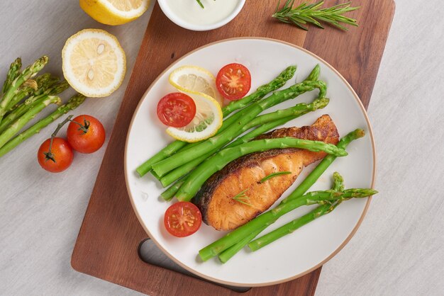 Deliciosos espárragos verdes y salmón ahumado en rodajas en un plato rústico