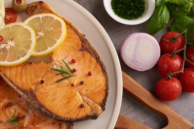 Deliciosos filetes de salmón cocidos. Filete de salmón a la plancha y ensalada de tomate vegetal con lechuga verde fresca. Concepto de nutrición equilibrada para una dieta mediterránea flexitariana de alimentación limpia.