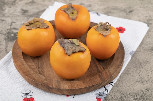 Deliciosos frutos de caqui maduros colocados en placa de madera