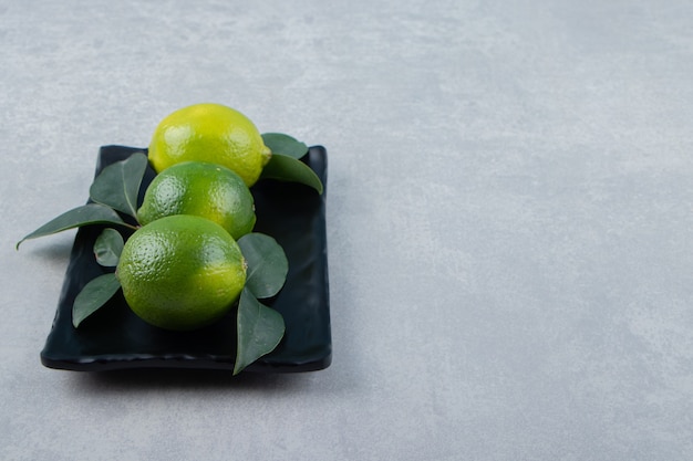 Foto gratuita deliciosos frutos de limón en placa negra