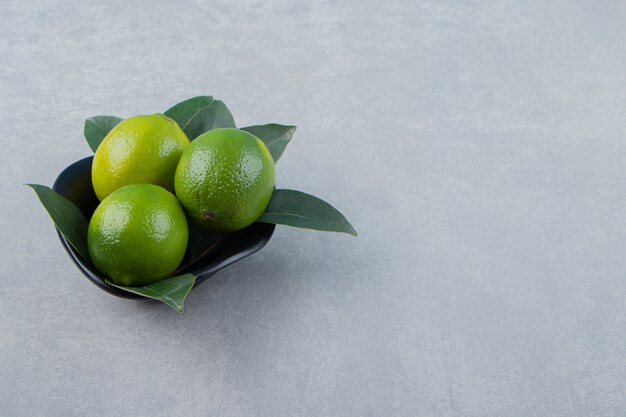 Deliciosos frutos de limón en un tazón negro.