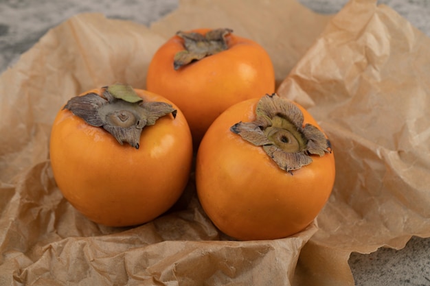 Foto gratuita deliciosos frutos maduros fuyu colocados en hoja de papel