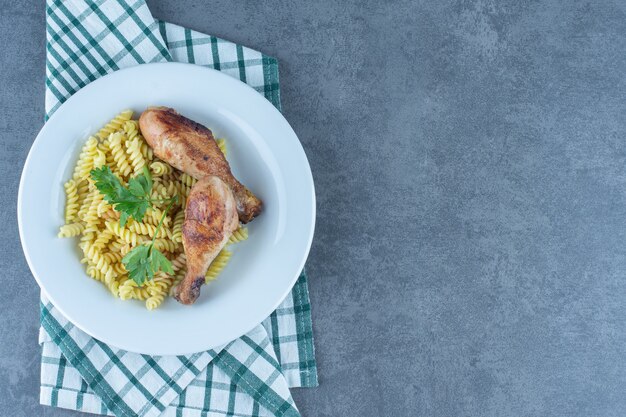 Deliciosos fusilli con muslos de pollo en un plato blanco.