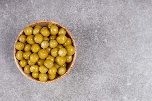 Deliciosos guisantes enlatados en tazón de madera