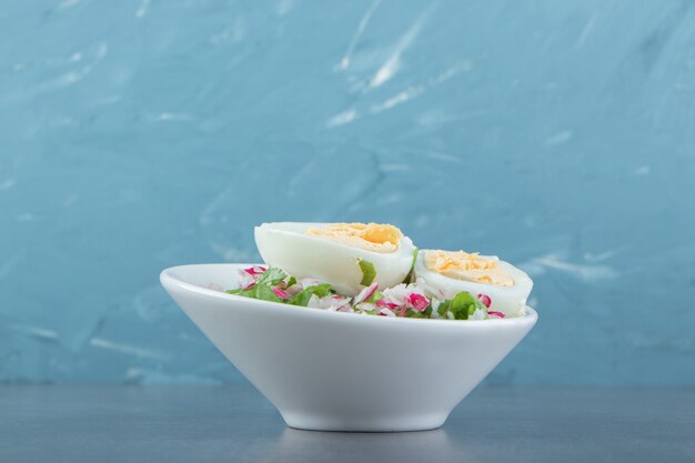 Deliciosos huevos duros y ensalada fresca en un tazón blanco