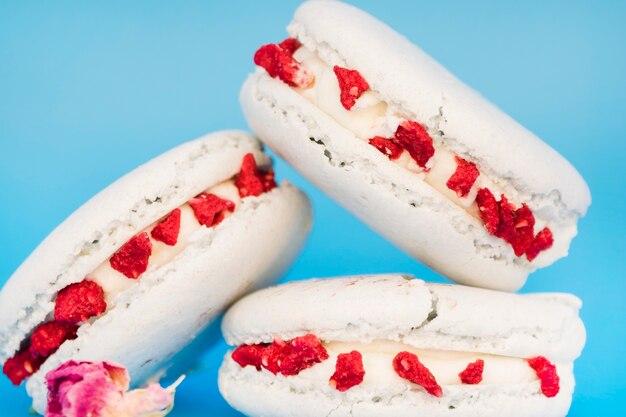 Deliciosos macarrones blancos con flores sobre fondo azul