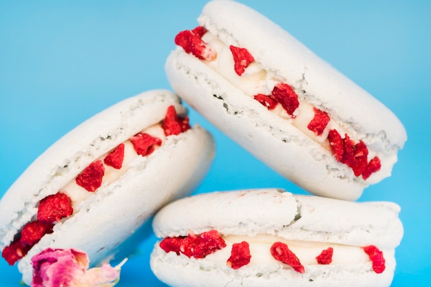 Deliciosos macarrones blancos con flores sobre fondo azul