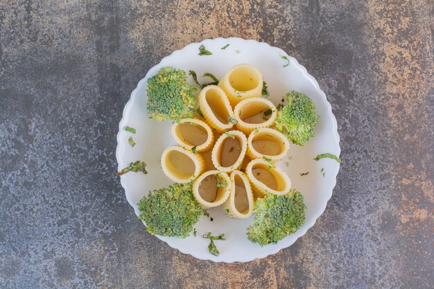 Deliciosos macarrones con brócoli en plato blanco.