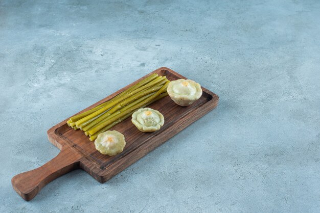Deliciosos mini calabacines en escabeche y palos sobre una tabla, sobre la mesa de mármol.