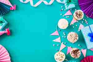 Foto gratuita deliciosos muffins con accesorios de fiesta en superficie verde.