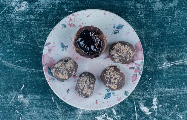Deliciosos muffins de chocolate en el plato, sobre el fondo azul.
