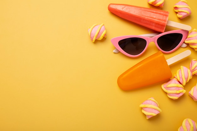 Foto gratuita deliciosos palitos de helado con gafas de sol