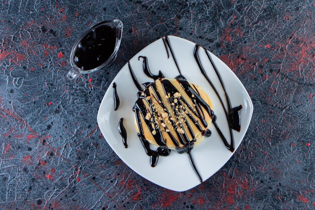 Deliciosos panqueques decorados con sirope de chocolate en un plato blanco.