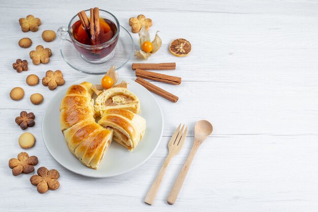 Deliciosos pasteles en rodajas dentro de la placa con relleno junto con té y galletas en blanco, pastelería galleta galleta dulce