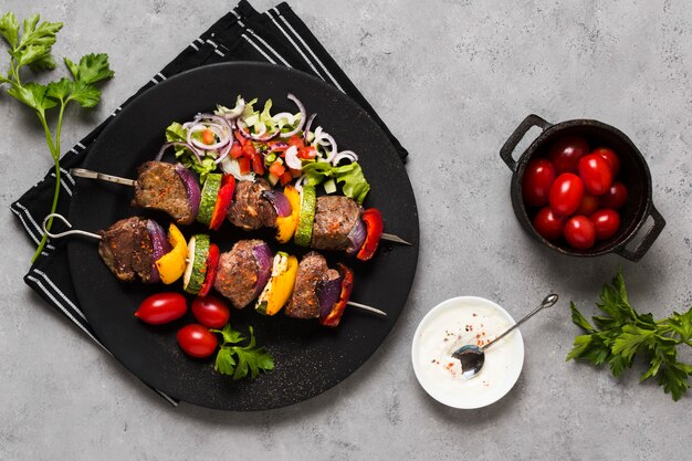 Deliciosos pinchos de comida rápida árabe en placa negra y tomates