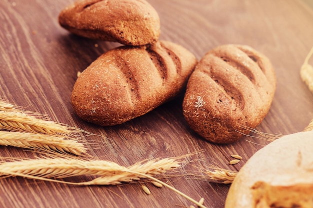 Deliciosos productos de panadería recién hechos y espiguillas de trigo sobre fondo de madera. Foto de primer plano de productos de pan recién horneados.