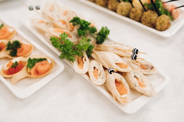 Deliciosos rollos de pescado y canapés con caviar rojo servidos en platos