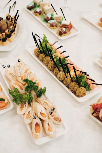 Deliciosos rollos de pescado y canapés con caviar rojo servidos en platos