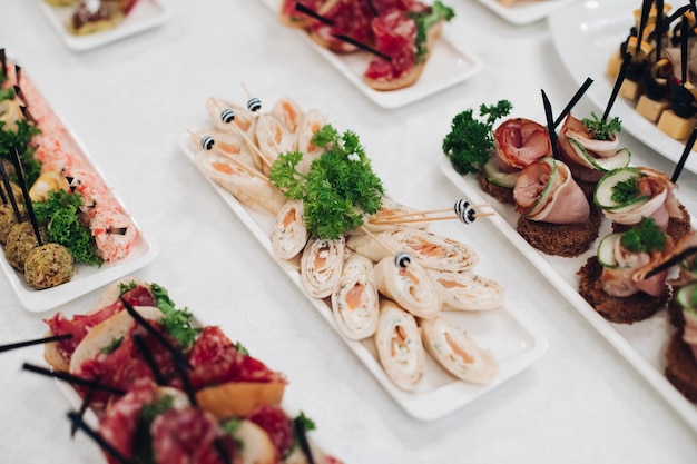 Deliciosos rollos de pescado y canapés con caviar rojo servidos en platos