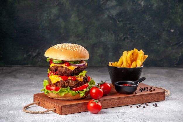 Deliciosos sándwich caseros tomates ketchup pimiento papas fritas en tabla de cortar en superficie borrosa