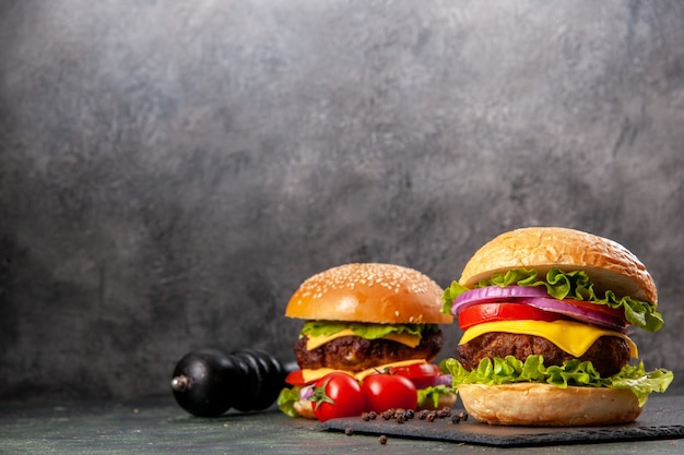 Deliciosos sándwiches de pimiento y tomates en una pizarra en el lado izquierdo sobre la superficie de color oscuro