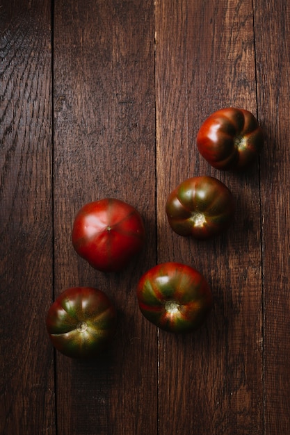 Deliciosos tomates en una vista superior de fondo de madera