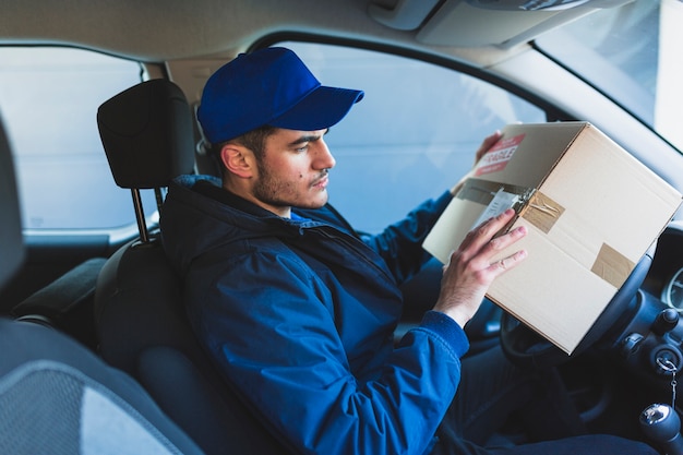 Deliveryman que controla la dirección en el paquete