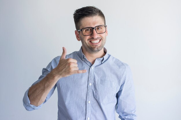 La demostración masculina joven emocionada alegre del encargado me llama gesto y la mirada de la cámara.