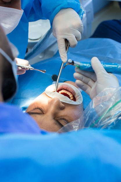 El dentista y el asistente con herramienta hacen algunas manipulaciones en la boca del paciente.